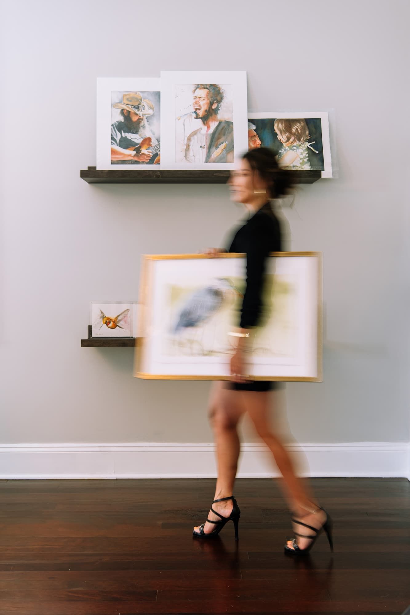 Deidre Husak moving through her studio with watercolors on display and in her hands. 